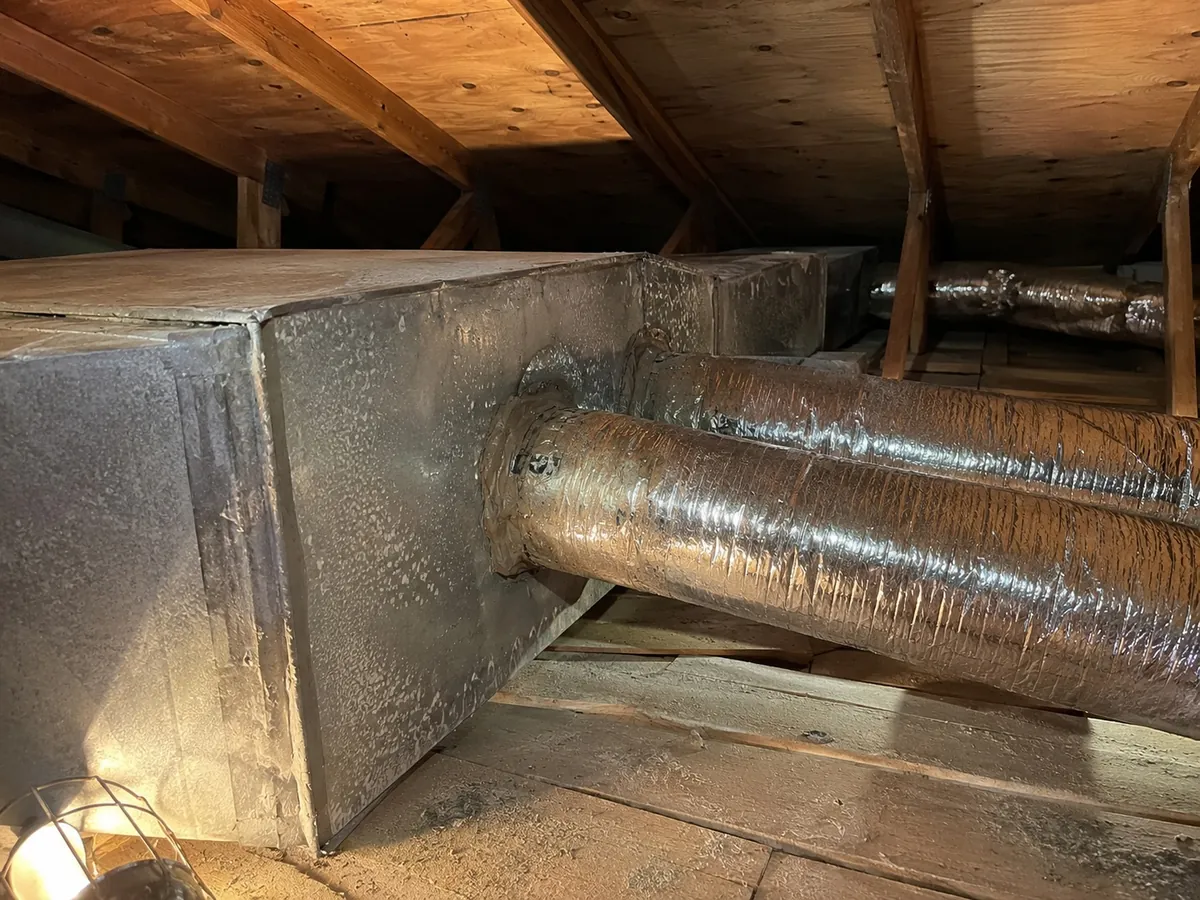 Attic ductwork showing a return plenum and several insulated supply branches with sealed connections